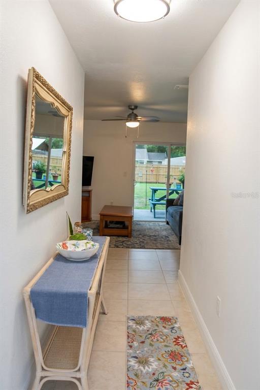 A hallway with a console table and mirror leads to a living room with patio access — 20367 ANDOVER AVENUE, PORT CHARLOTTE, FL