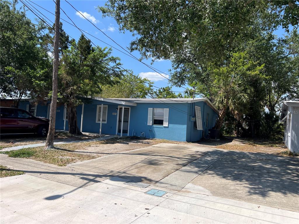 A blue single-story house with a concrete driveway and mature trees in the front yard — 21274 COULTON AVENUE, PORT CHARLOTTE, FL