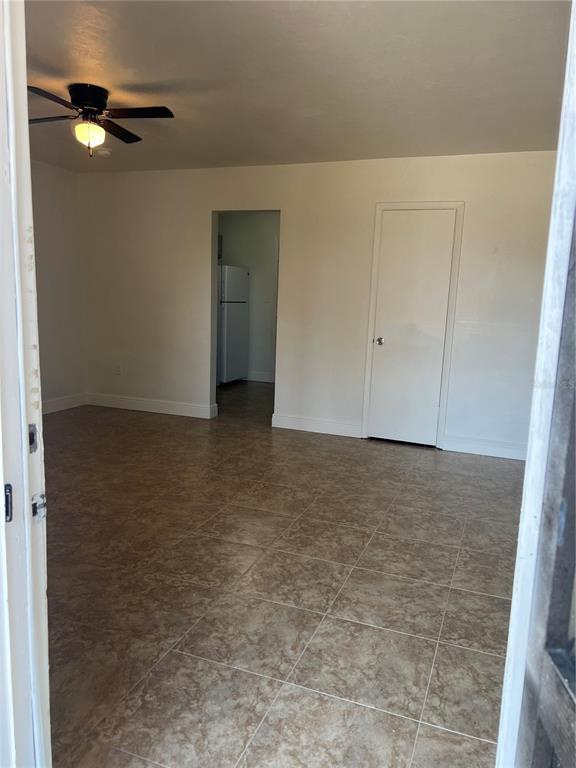 An interior view of a room with tiled floors, a ceiling fan, and a doorway — 21274 COULTON AVENUE, PORT CHARLOTTE, FL