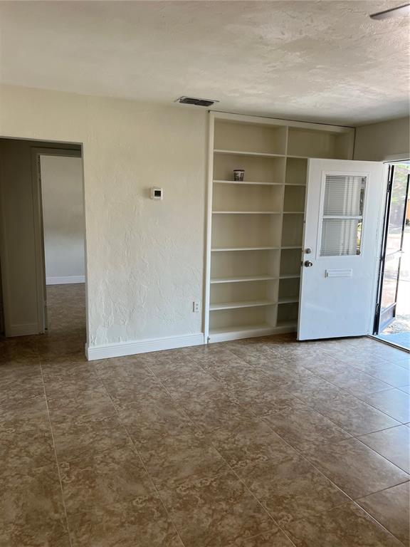 A room with tiled floors, built-in shelving, and an open door leading outside — 21274 COULTON AVENUE, PORT CHARLOTTE, FL
