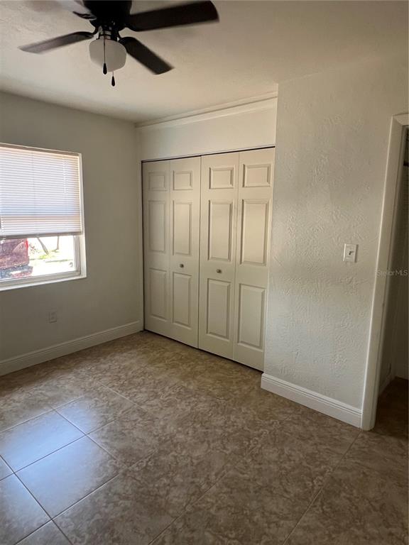 A bedroom with tiled floors, a ceiling fan, and a white bi-fold closet door — 21274 COULTON AVENUE, PORT CHARLOTTE, FL