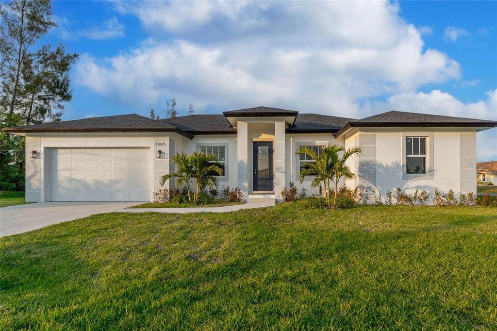 A single-story white house with a two-car garage and a central entryway — 10625 AYEAR ROAD, PORT CHARLOTTE, FL