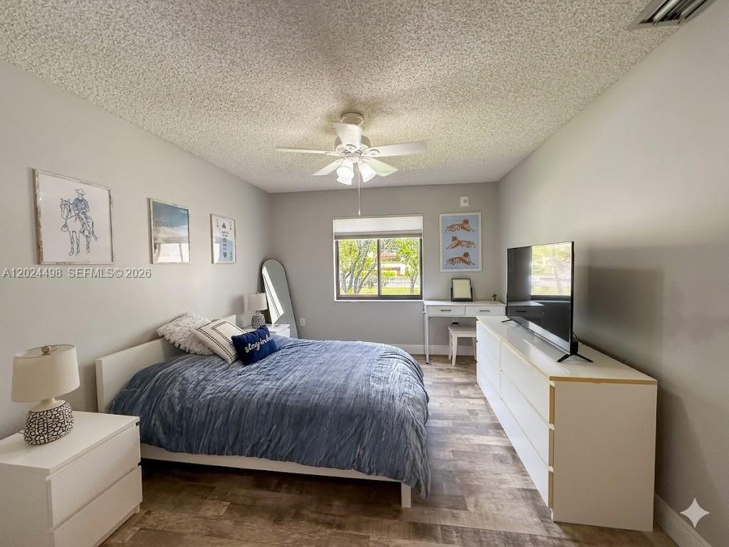 A bedroom features a bed with blue bedding, a white dresser, and a desk — 8911 SW 123rd Ct # 203, Miami FL 33186, MIAMI, FL