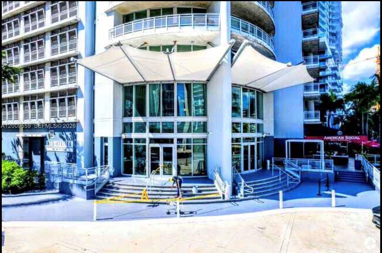 The exterior of a modern high-rise building features a white fabric canopy over the entrance — 690 SW 1st Ct, Miami FL 33130, MIAMI, FL