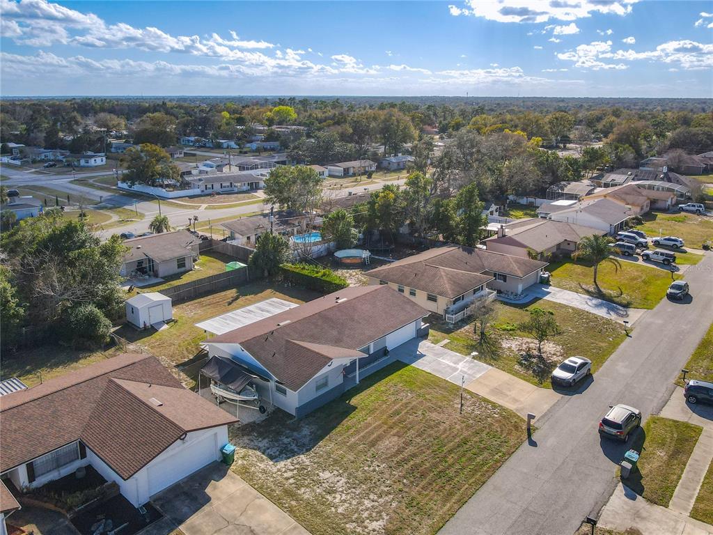 An aerial view shows several suburban houses with brown roofs, driveways, and backyards on a sunny day — 895 SUPERIOR STREET, DELTONA, FL