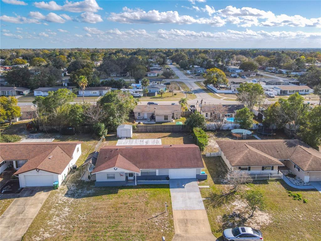 An aerial view shows a single-story house with a brown roof and a concrete driveway — 895 SUPERIOR STREET, DELTONA, FL