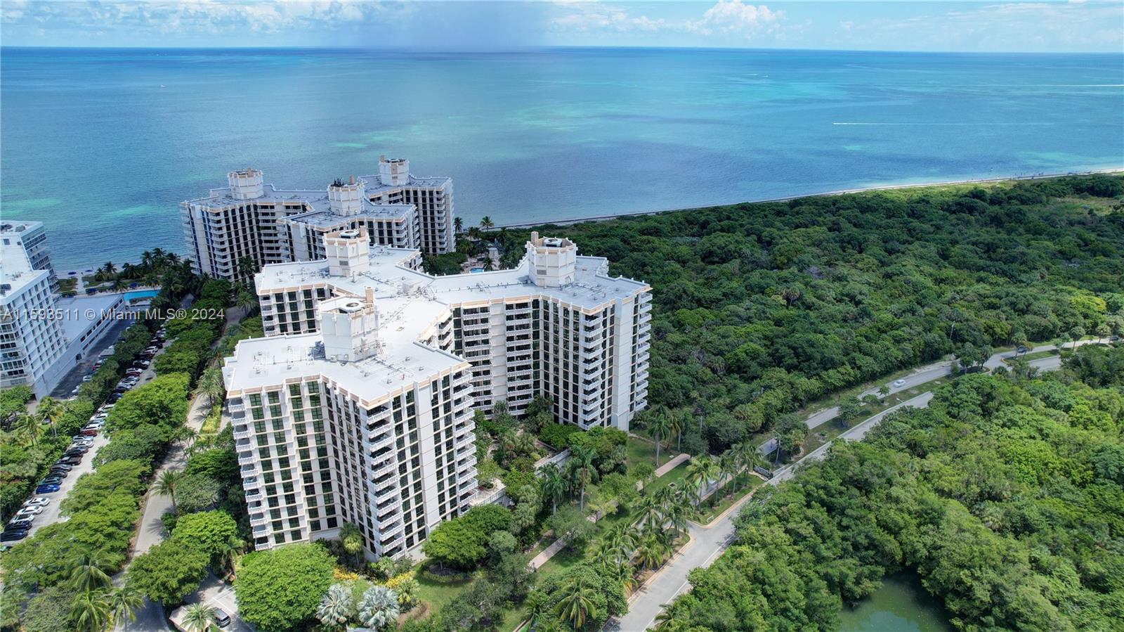 An aerial view shows a large residential complex surrounded by dense forest near the ocean — 1121 Crandon Blvd # D1201, Key Biscayne FL 33149, KEY BISCAYNE, FL