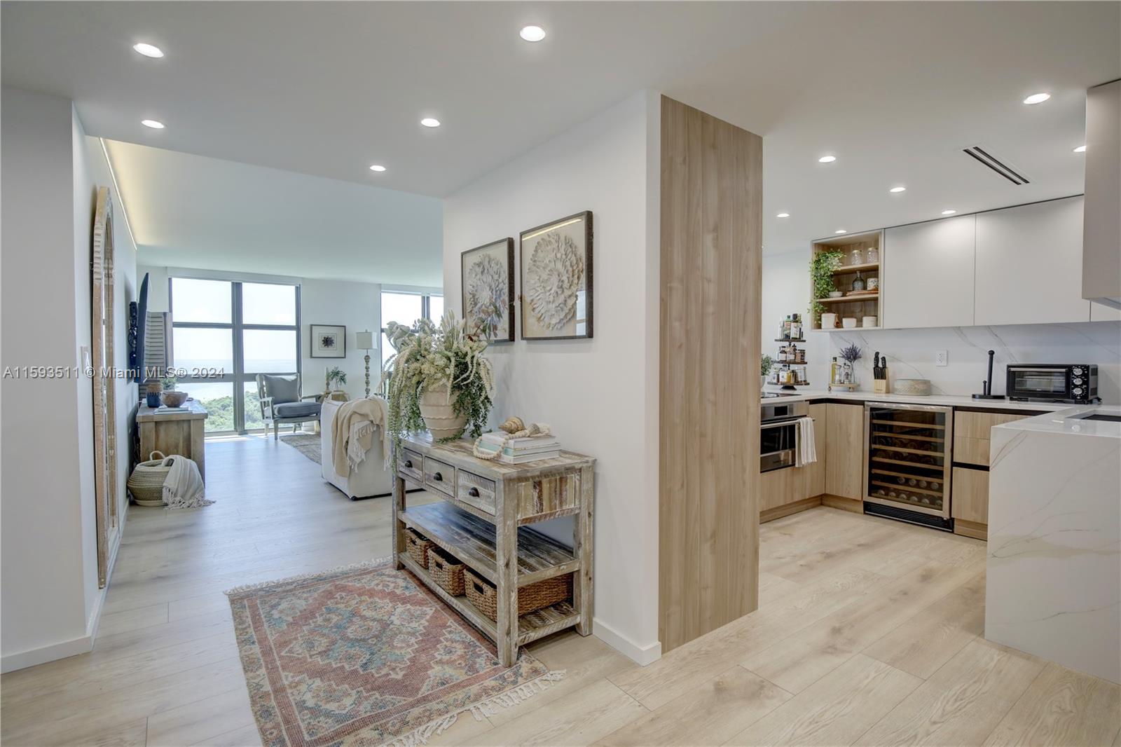 A modern kitchen and living area feature light wood flooring, white cabinetry, and coastal decor — 1121 Crandon Blvd # D1201, Key Biscayne FL 33149, KEY BISCAYNE, FL