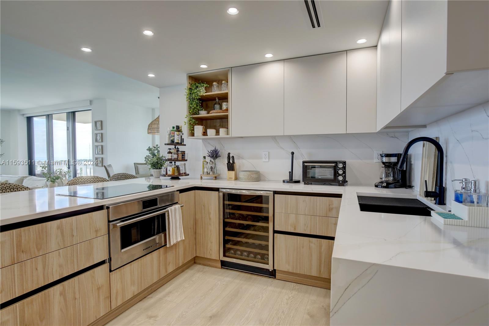 A modern kitchen features light wood cabinets, white marble countertops, and a built-in wine cooler — 1121 Crandon Blvd # D1201, Key Biscayne FL 33149, KEY BISCAYNE, FL