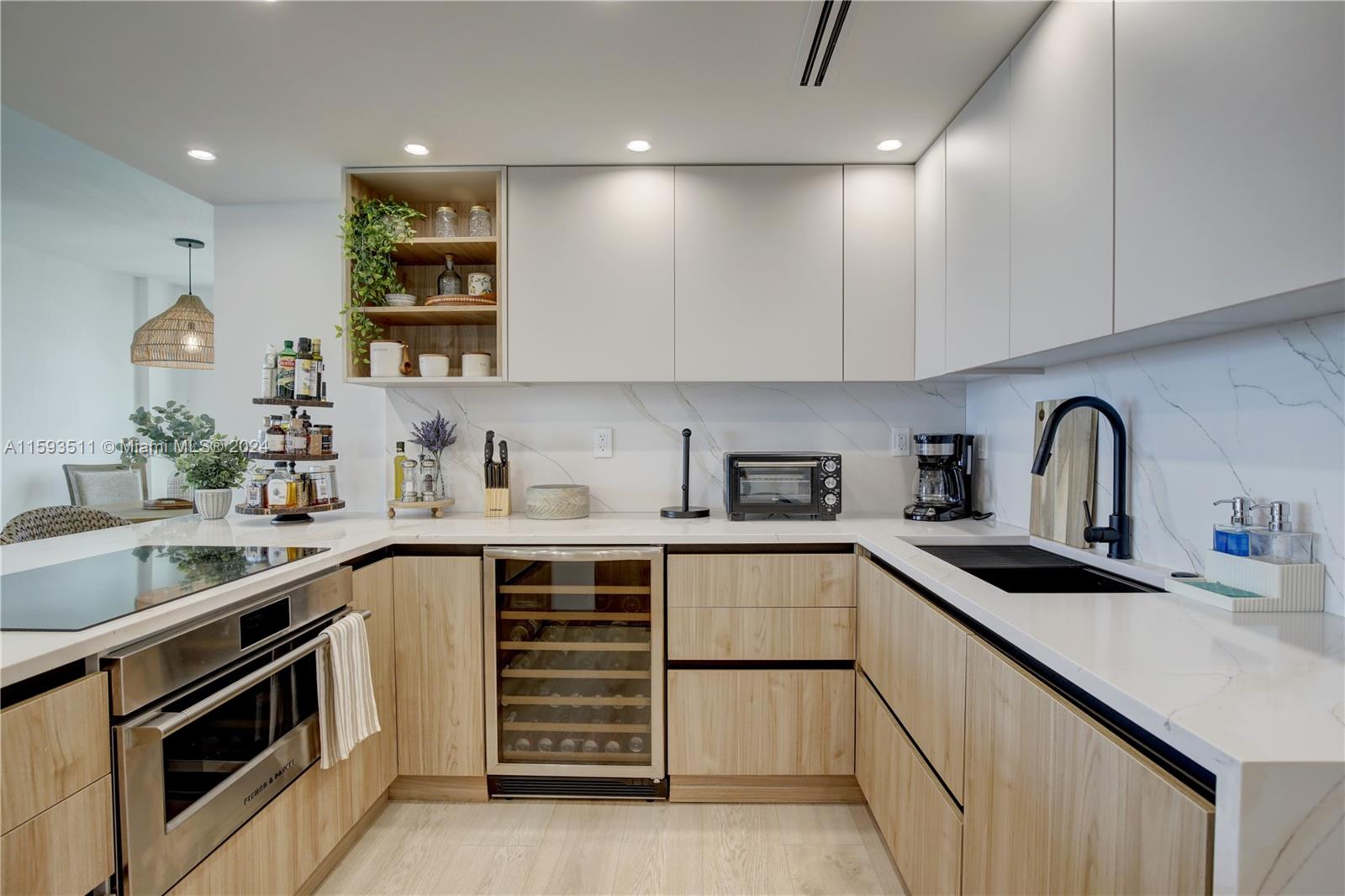 A modern kitchen features light wood cabinets, white countertops, a wine cooler, and marble backsplash — 1121 Crandon Blvd # D1201, Key Biscayne FL 33149, KEY BISCAYNE, FL