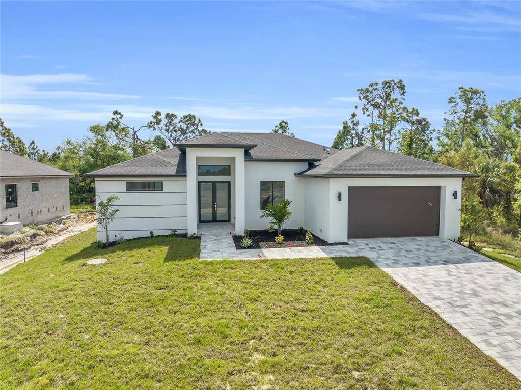 A modern single-story house with white stucco walls, a dark roof, and a paved driveway — 9108 SANTA LUCIA DRIVE, PORT CHARLOTTE, FL