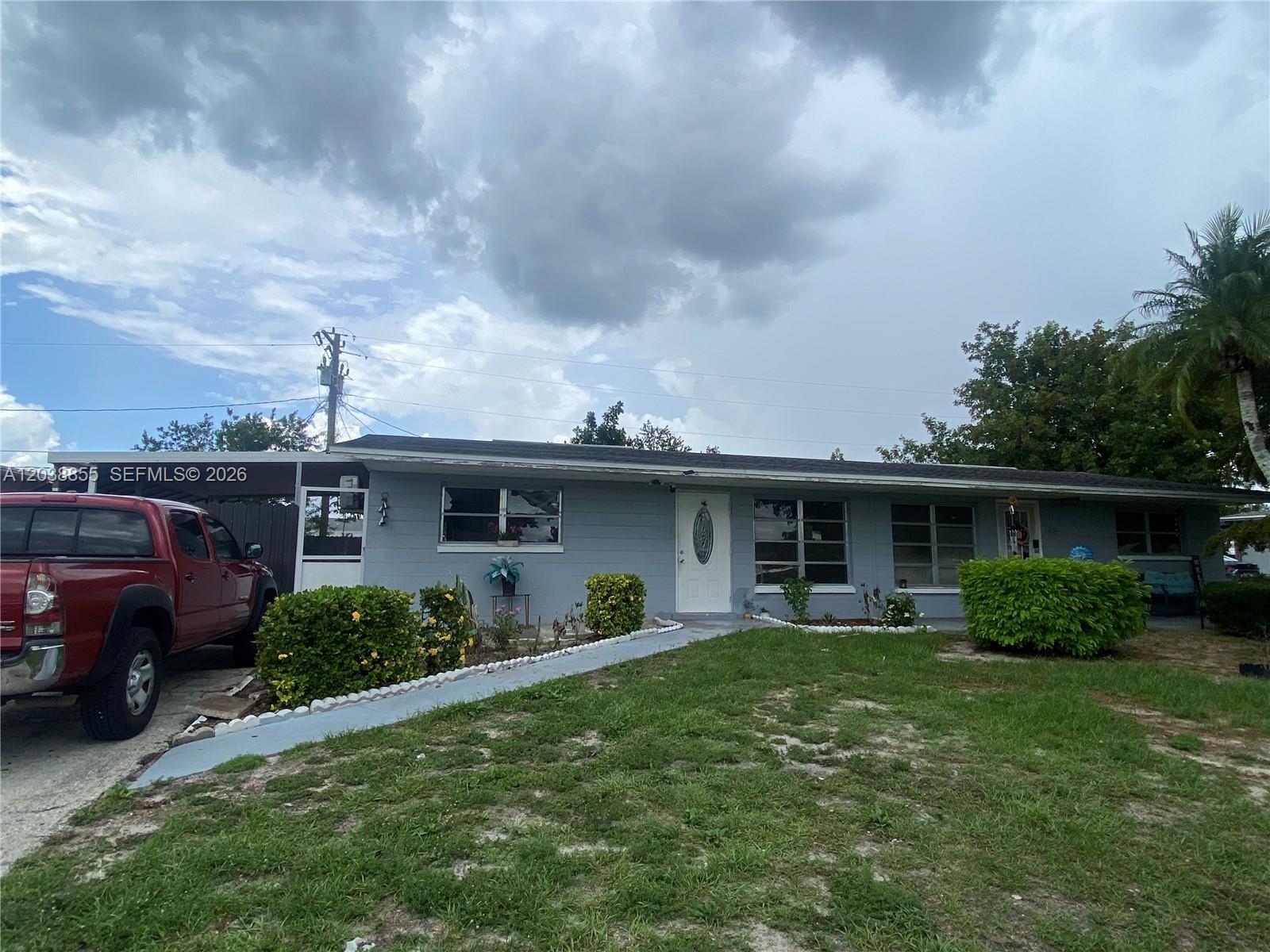 A single-story gray house with a red truck parked in the driveway — 1111 N VINEYARD ST, Lehigh Acres FL 33936, LEHIGH ACRES, FL