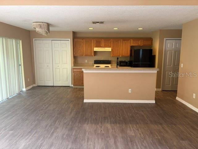A kitchen with wood cabinets and a breakfast bar opens to a living area — 2014 STONE ABBEY BOULEVARD, ORLANDO, FL
