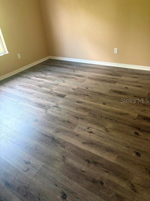 An empty room with tan walls and dark wood-look laminate flooring — 2014 STONE ABBEY BOULEVARD, ORLANDO, FL