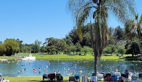 A large outdoor swimming pool is surrounded by a grassy park with trees and palm trees — SANTURCE AVENUE, NORTH PORT, FL
