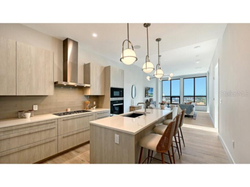 A modern kitchen features light wood cabinets, a central island with bar seating, and pendant lights — 33 S PALM AVENUE UNIT 904, SARASOTA, FL