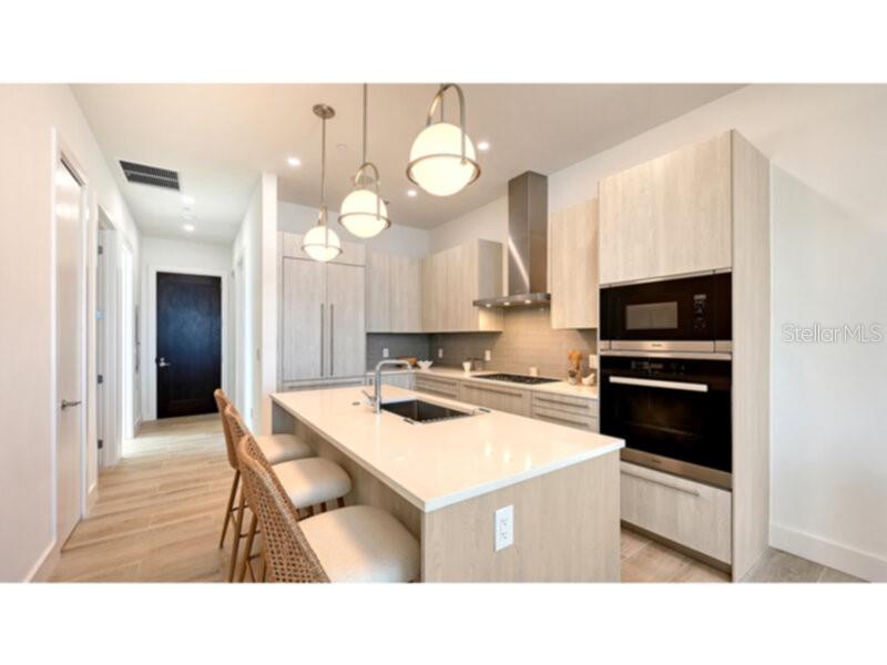 A modern kitchen features light wood cabinetry, a white quartz island, and three pendant lights — 33 S PALM AVENUE UNIT 904, SARASOTA, FL
