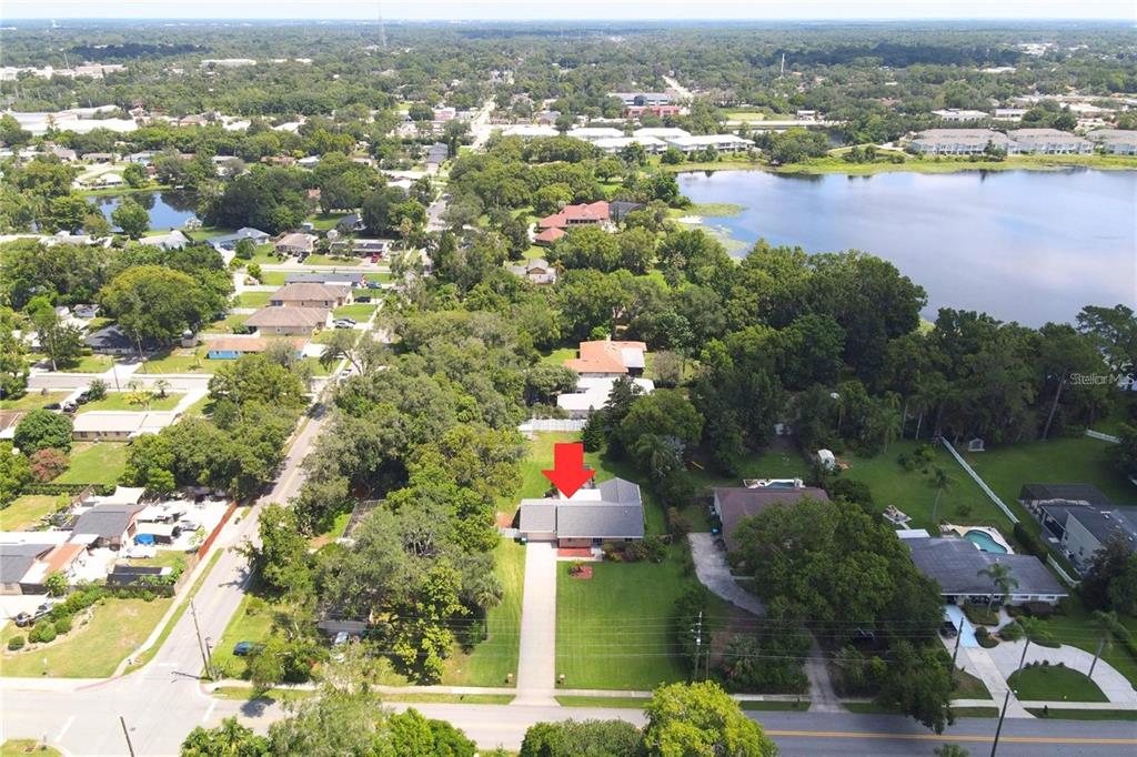An aerial view shows a single-story house with a red arrow pointing to its roof — 513 E WILDMERE AVENUE, LONGWOOD, FL