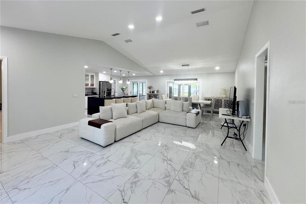 A spacious open-concept living area features a large sectional sofa and white marble-look tile flooring — 513 E WILDMERE AVENUE, LONGWOOD, FL