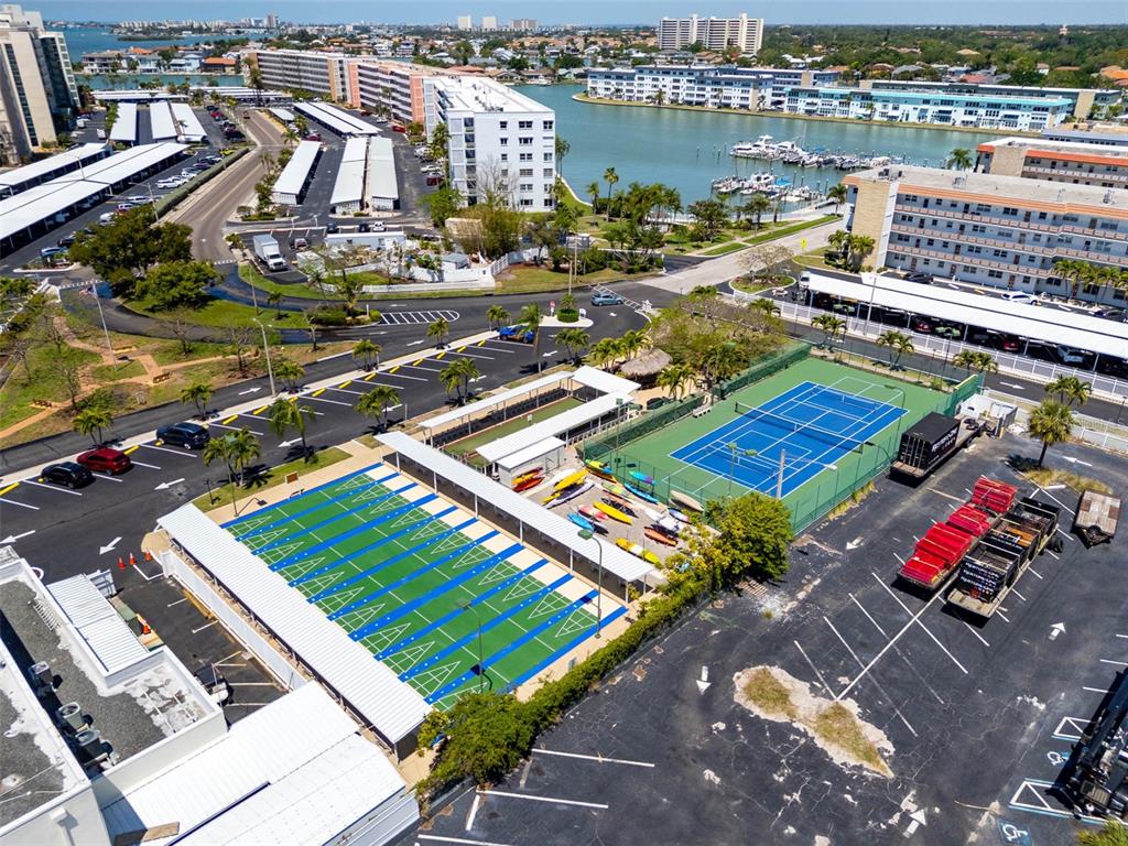 An aerial view shows a tennis court, shuffleboard courts, and a parking lot near water — 2850 59TH STREET S UNIT 215, GULFPORT, FL