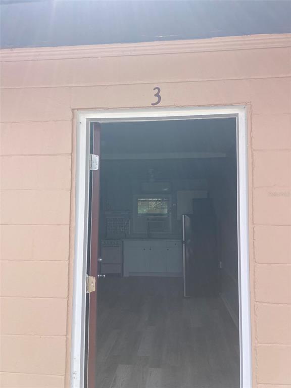 A view through an open doorway into a small kitchen with light-colored cabinets — 1401 E ALFRED STREET UNIT 3, TAVARES, FL