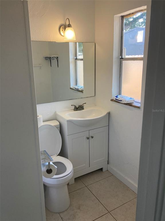 A small bathroom features a white vanity with a sink, a toilet, and a wall mirror — 1401 E ALFRED STREET UNIT 3, TAVARES, FL