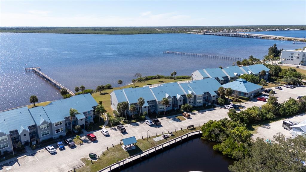 An aerial view shows waterfront condominiums with blue metal roofs, parking lots, and wooden piers — 4410 WARREN AVENUE UNIT 216, PORT CHARLOTTE, FL