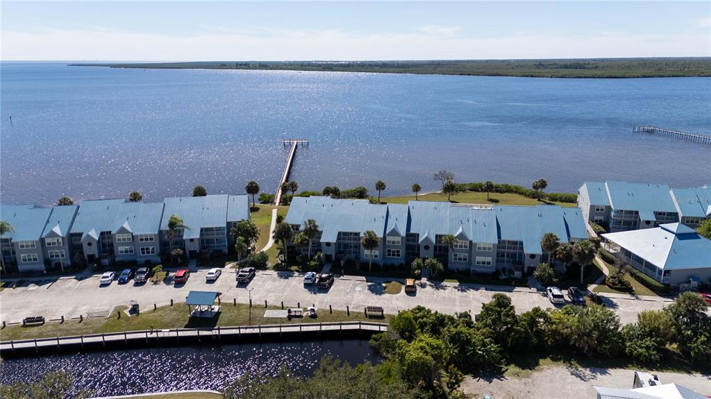 An aerial view shows waterfront condominium buildings with blue metal roofs and a wooden pier — 4410 WARREN AVENUE UNIT 216, PORT CHARLOTTE, FL