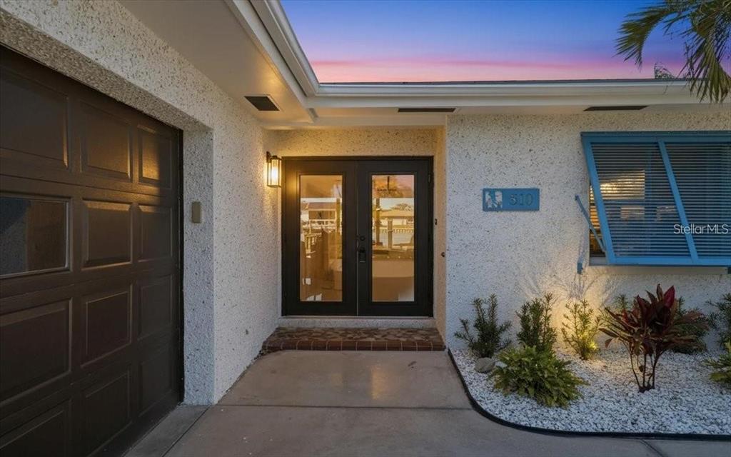 The exterior of a home features a concrete porch, double glass doors, and a garage — 510 115TH AVENUE, TREASURE ISLAND, FL