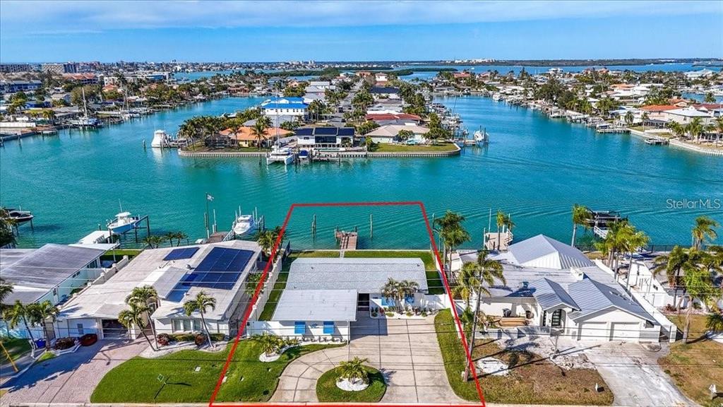 An aerial view shows a waterfront house with a private dock and a circular driveway — 510 115TH AVENUE, TREASURE ISLAND, FL