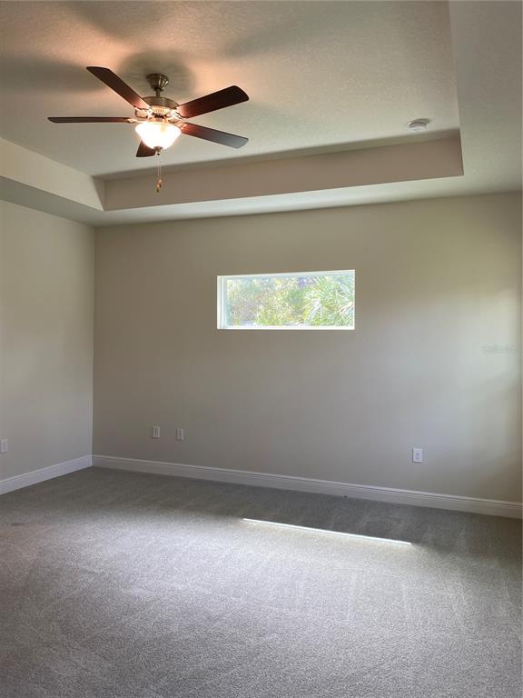 A bedroom with neutral walls, gray carpet, a tray ceiling, and a small rectangular window — 3481 NASHVILLE ROAD, NORTH PORT, FL
