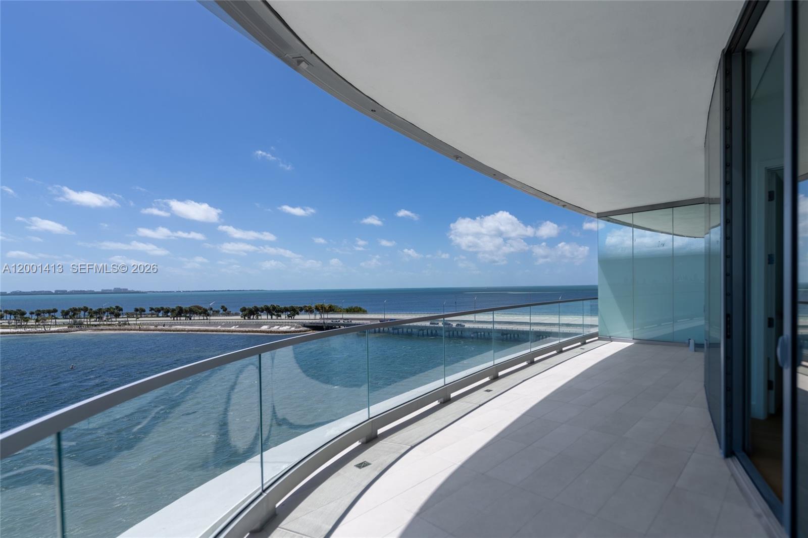 A curved balcony with a glass railing overlooks the ocean and a bridge — 175 SE 25 Rd # 501, Miami FL 33129, MIAMI, FL