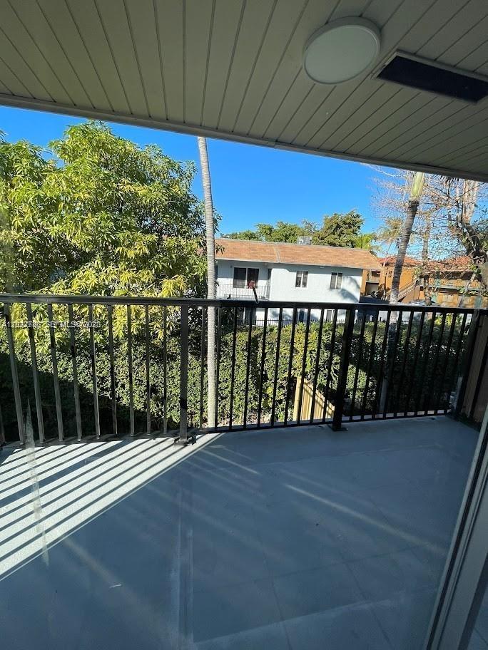 A balcony with a black metal railing overlooks a tree-lined residential street — 4271 NW 11th St # 1, Miami FL 33126, MIAMI, FL