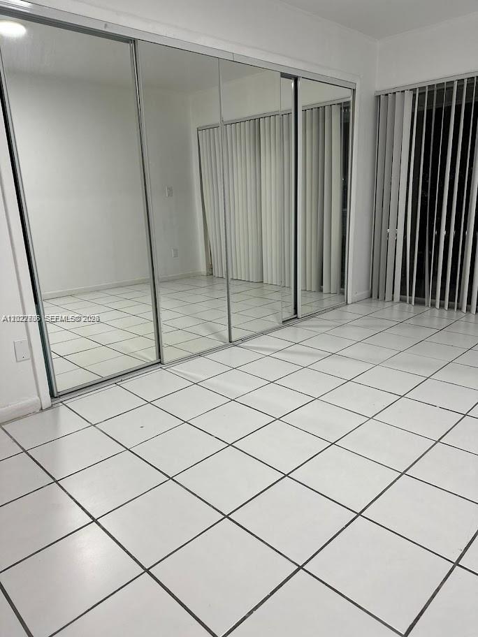 A room with white tiled floors and a large sliding mirrored closet door — 4271 NW 11th St # 1, Miami FL 33126, MIAMI, FL