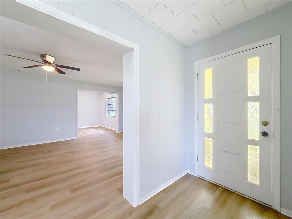 An entryway with light wood flooring leads into a living room with a ceiling fan — 11900 SE SUNSET HARBOR ROAD, WEIRSDALE, FL