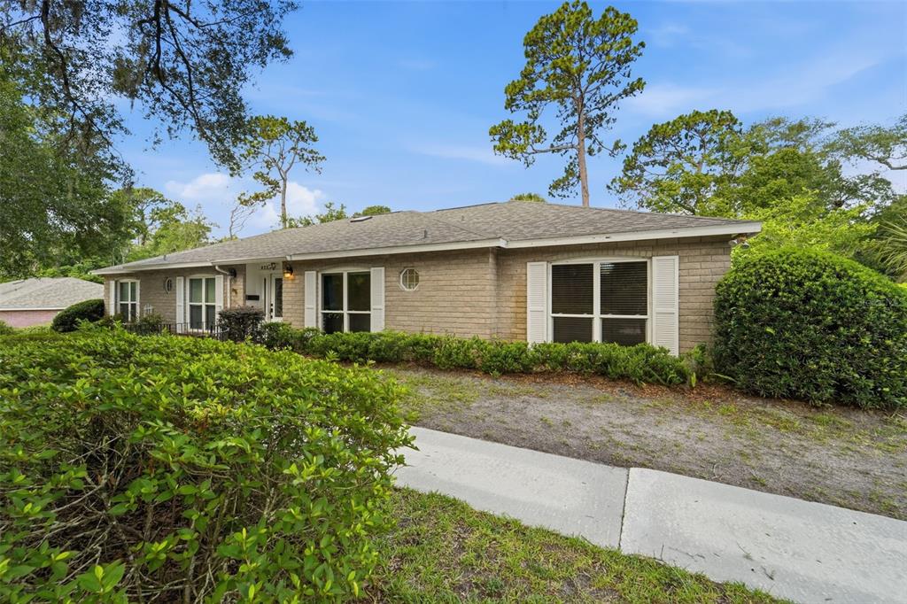 A single-story brick house with a shingled roof sits behind a manicured hedge and walkway — 820 S HILL AVENUE UNIT 40, DELAND, FL