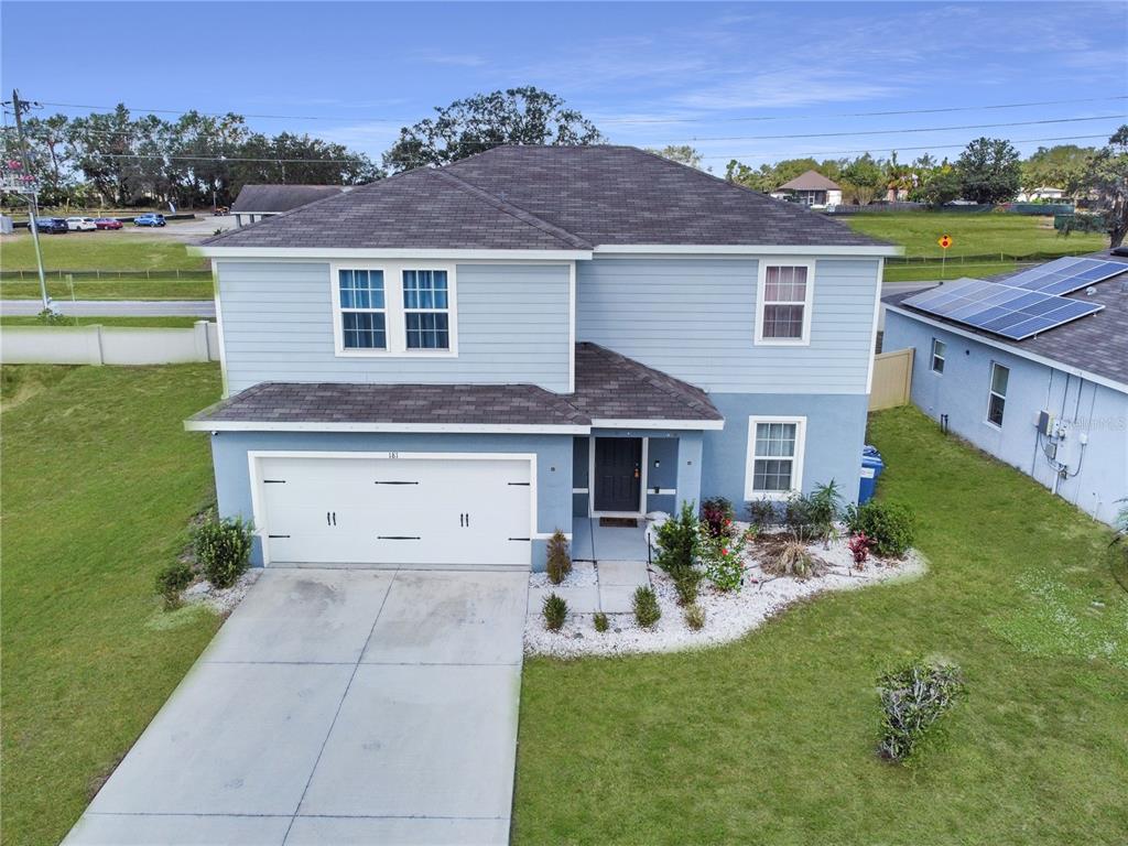 An aerial view of a two-story blue house with a two-car garage and driveway — 181 SILVER MAPLE BEND, DAVENPORT, FL
