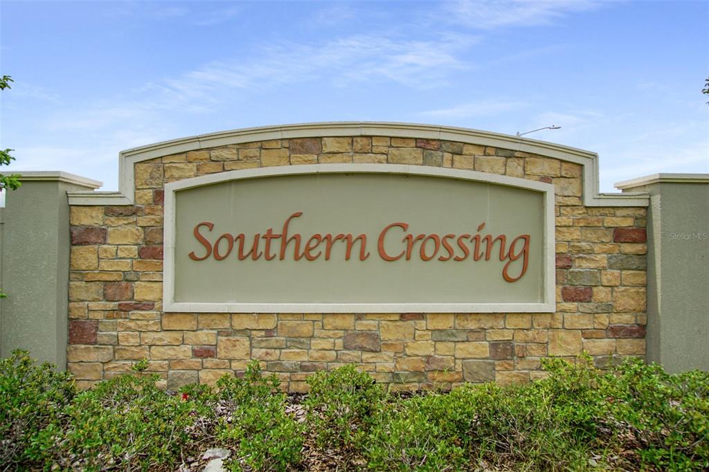 A stone monument sign displays the name Southern Crossing against a blue sky — 181 SILVER MAPLE BEND, DAVENPORT, FL