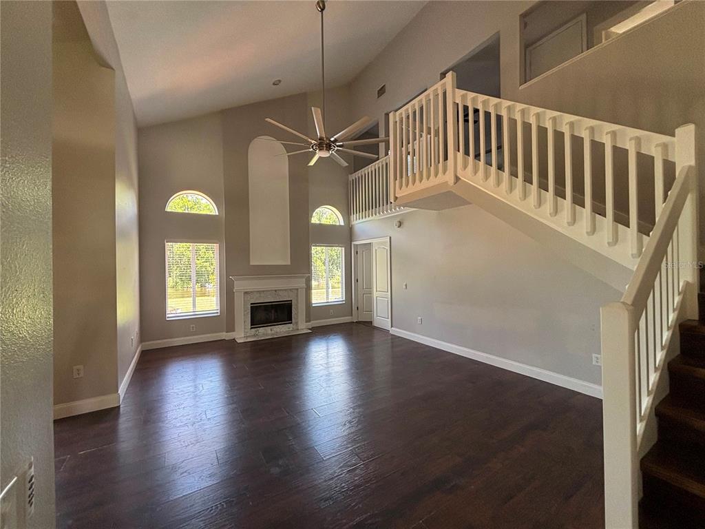 A living room with dark wood floors, a fireplace, and a staircase to a loft — 3231 CASTLE ROCK CIRCLE, LAND O LAKES, FL