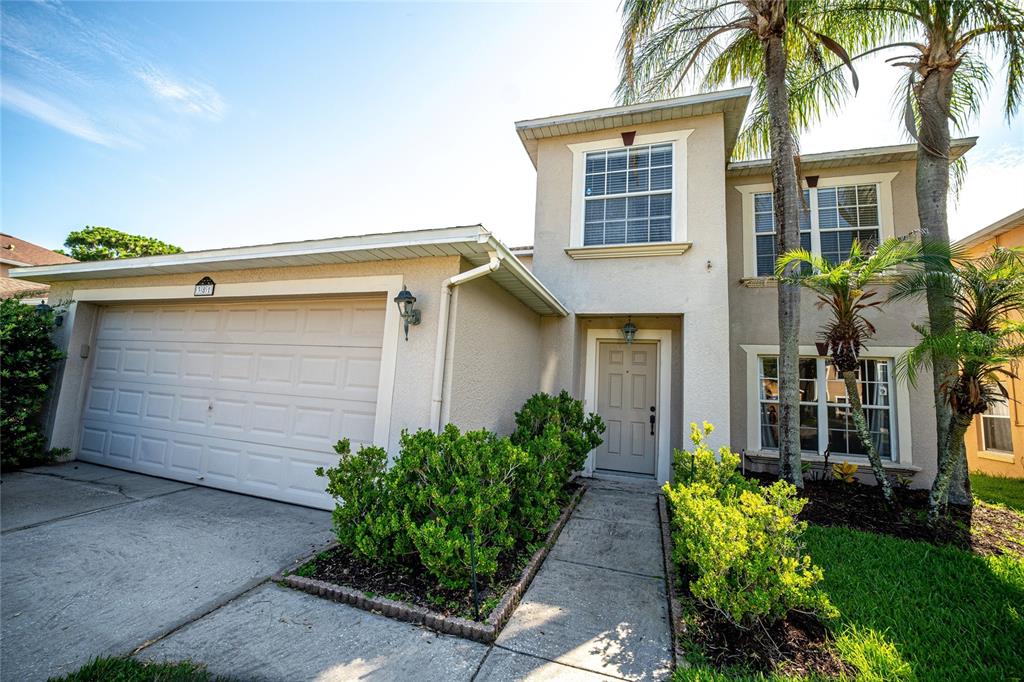 A two-story house with a beige stucco exterior, a single-car garage, and palm trees — 381 AUGUSTINE COURT, OVIEDO, FL