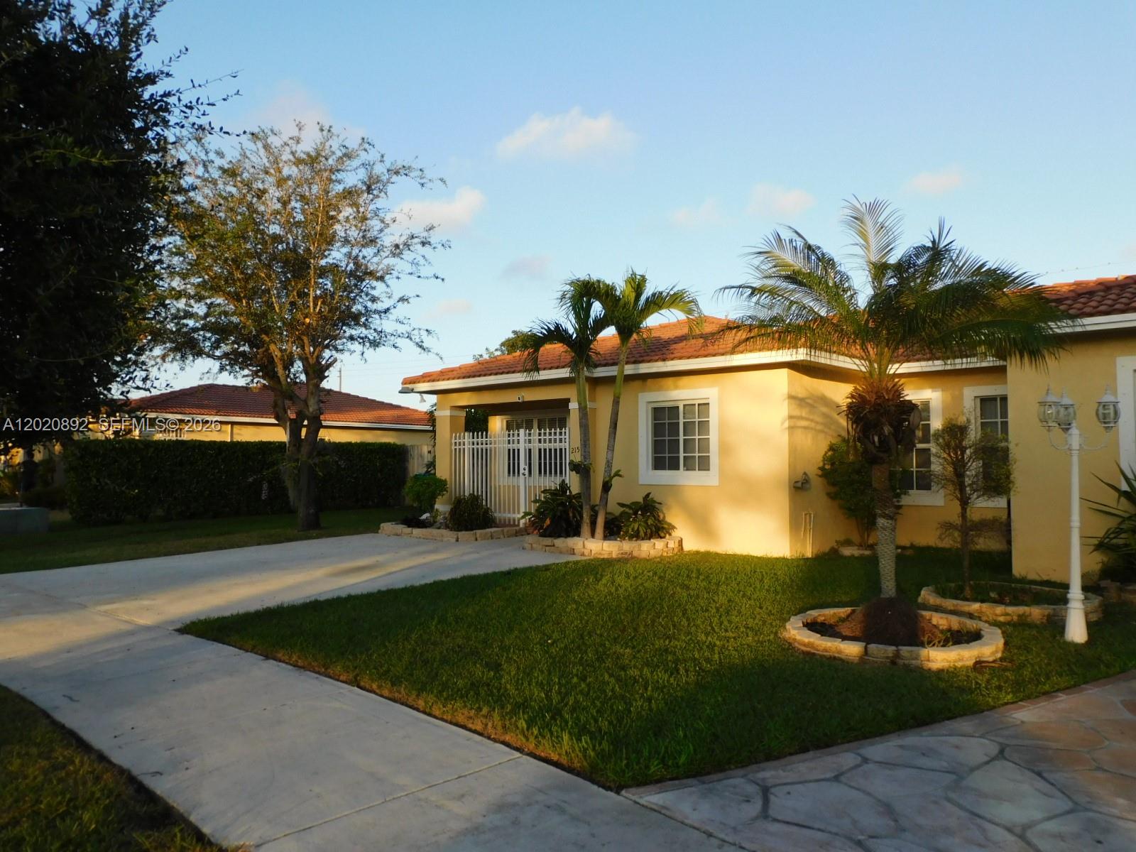 A single-story yellow house with a tile roof, palm trees, and a concrete driveway — 21511 SW 122nd Ct # 0, Miami FL 33177, MIAMI, FL