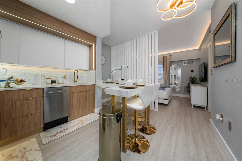 A kitchen and dining area feature wood cabinets, white upper cabinets, and gold bar stools — 7601 CANADA AVENUE UNIT 614, ORLANDO, FL