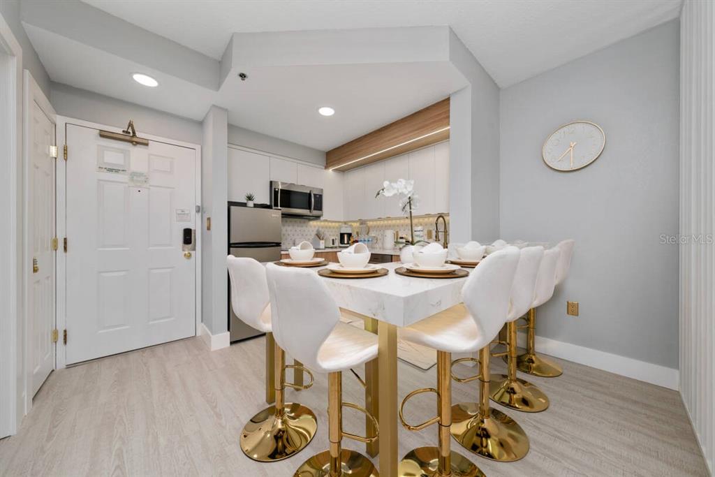 A kitchen and dining area features a marble-topped table with gold-based white stools — 7601 CANADA AVENUE UNIT 614, ORLANDO, FL