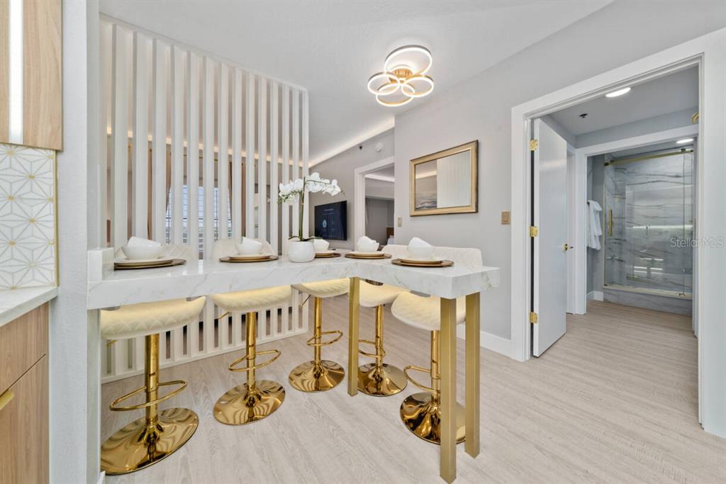 A kitchen breakfast bar with gold stools sits before a slatted room divider — 7601 CANADA AVENUE UNIT 614, ORLANDO, FL