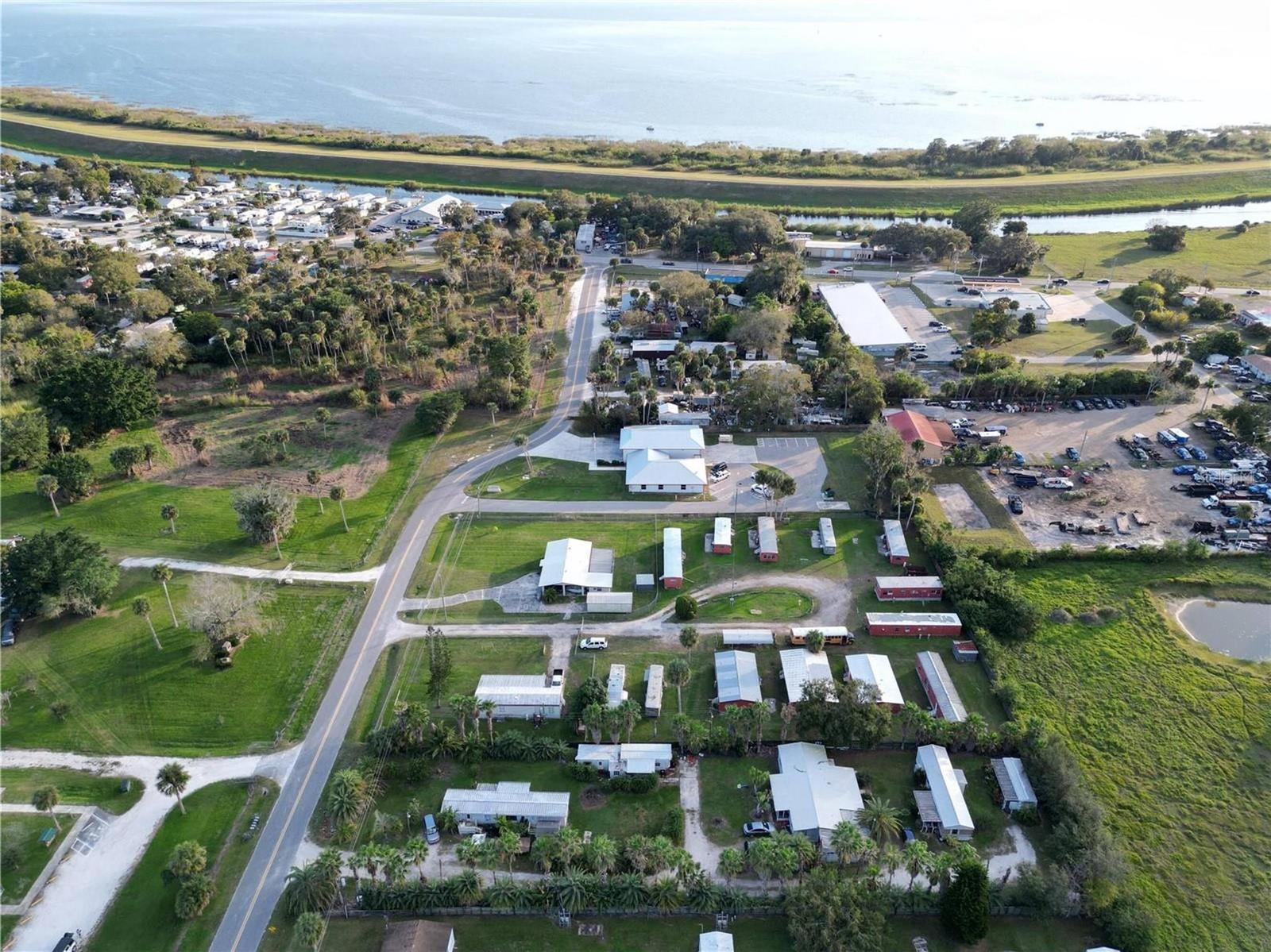 An aerial view shows a residential area with mobile homes, a road, and nearby water — 3431 38th Avenue, Okeechobee FL 34974, OKEECHOBEE, FL