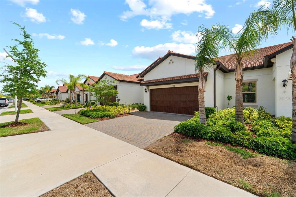 A street-level view of a suburban house with a paved driveway and a brown garage — 17538 HOLLY WELL AVENUE, WIMAUMA, FL