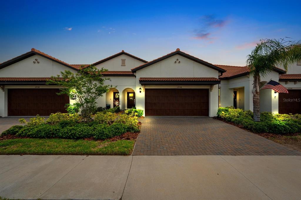 A single-story house with a tiled roof, two garage doors, and a paved driveway — 17538 HOLLY WELL AVENUE, WIMAUMA, FL