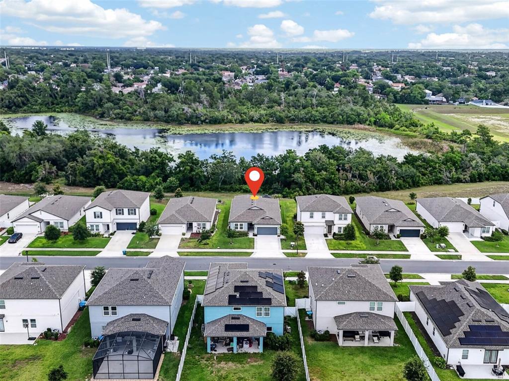 An aerial view shows a suburban neighborhood with houses, a lake, and a red location pin — 1196 PEARL TREE ROAD, DELTONA, FL