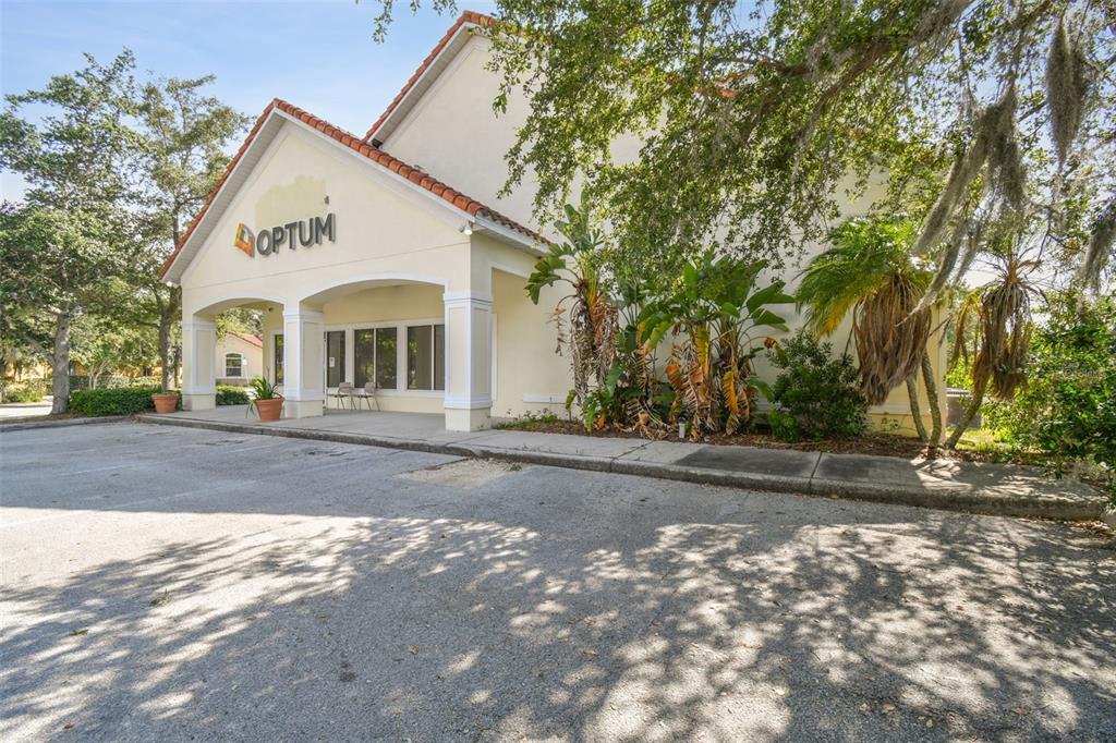 A single-story commercial building with an Optum sign, a covered entrance, and surrounding trees — 772 CORTARO DRIVE, SUN CITY CENTER, FL