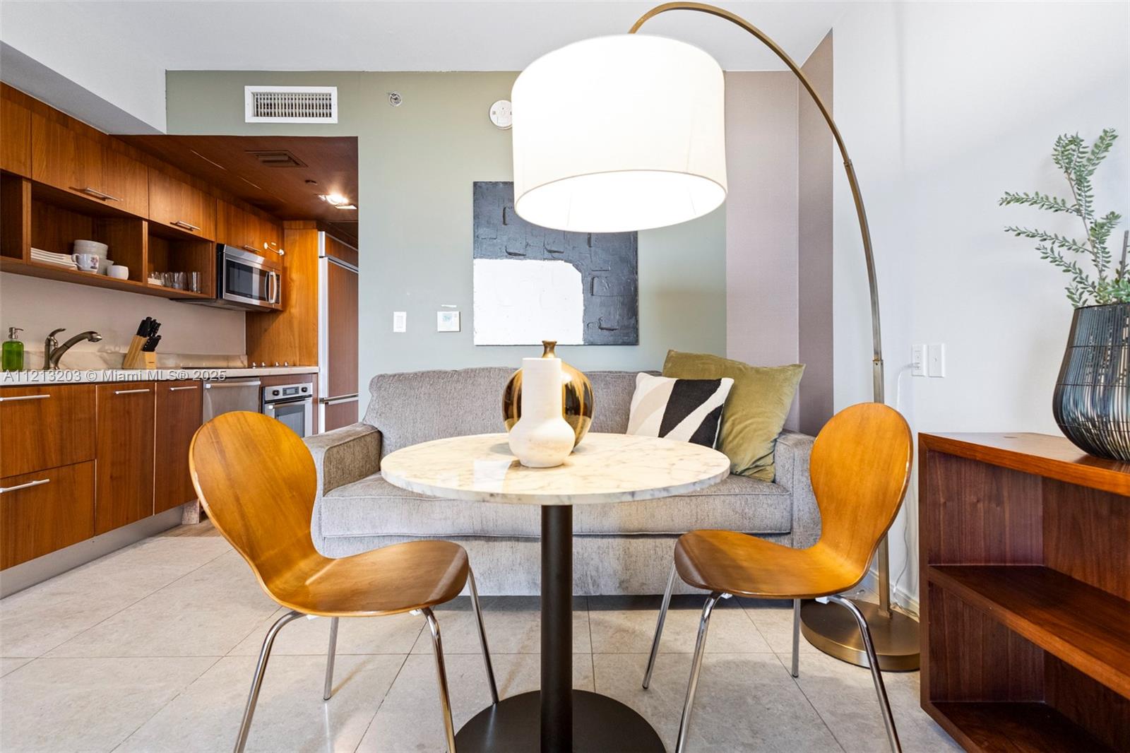 A small dining area with a marble table and two wooden chairs sits before a sofa — 50 Biscayne Blvd # 605, Miami FL 33132, MIAMI, FL
